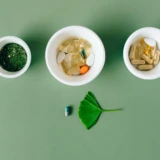 Vitaminer og mineraler sorteret i små skåle på grøn baggrund