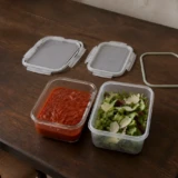 Madopbevaring i glas og plast med kompatible låg på et mørkt spisebord