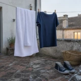 Rent håndklæde, mørkeblå T-shirt og åbne sko til tørre i en taggård