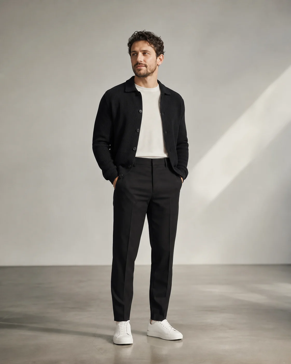 Lav mand i cremehvid t-shirt, kort sort cardigan, sorte bukser og hvide sneakers