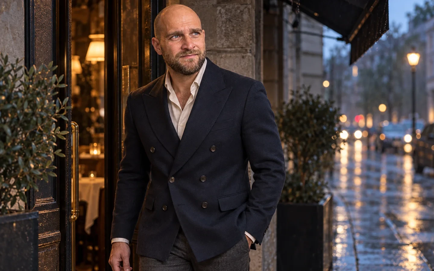 Mand i navy dobbeltradet blazer ved en restaurantindgang i aftenlys