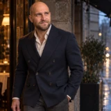 Mand i navy dobbeltradet blazer ved en restaurantindgang i aftenlys