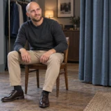Siddende mand i sandfarvede chinos med hele buksebenet synligt