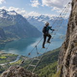 Illustration af en sikret klatrer på en skrå stige over en norsk fjord