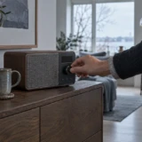 Hånd der tænder en DAB-radio på en skænk i et moderne hjem
