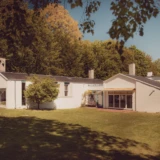 Finn Juhls hvide hus set fra haven med store vinduer og skov i baggrunden